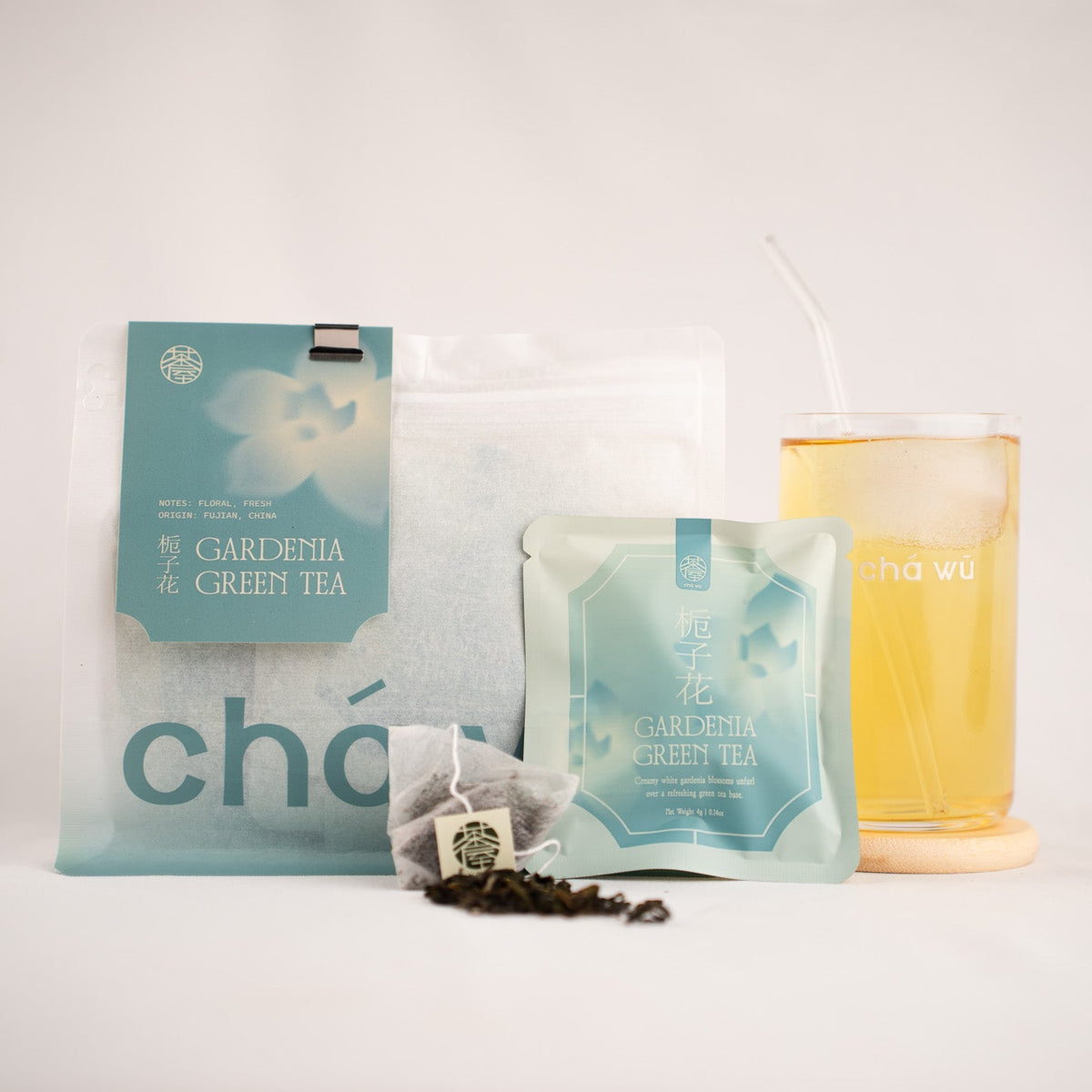 A package of CHAWU Gardenia Green Tea tea set on a white background, featuring a large resealable pouch, a smaller sachet, loose tea leaves, and a glass of brewed tea with a tea bag.